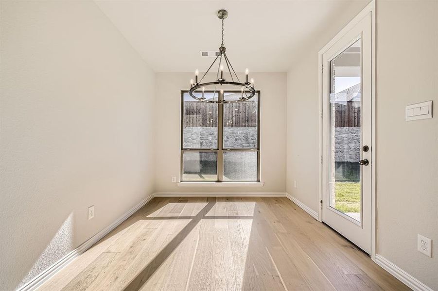 Unfurnished dining area featuring a chandelier and light hardwood / wood-style flooring