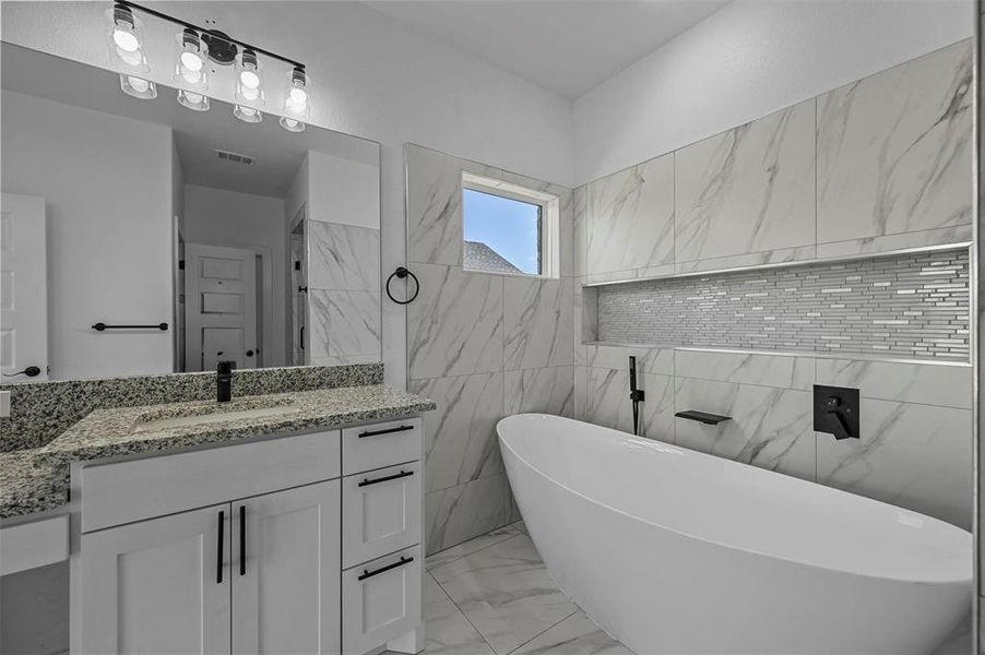 Bathroom with tile walls, tile patterned floors, a bath, and vanity