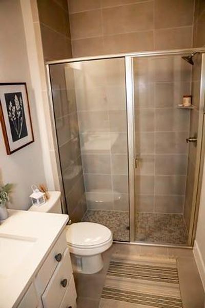 Bathroom with tile patterned flooring, vanity, toilet, and a shower with door