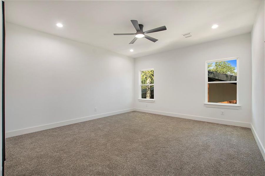 Carpeted spare room featuring ceiling fan and plenty of natural light