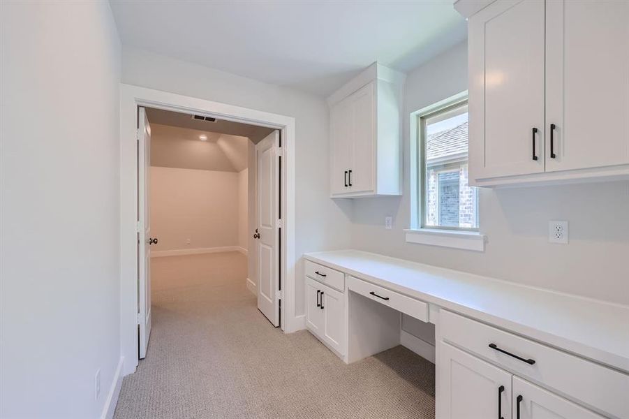 Unfurnished office with built in desk and light colored carpet