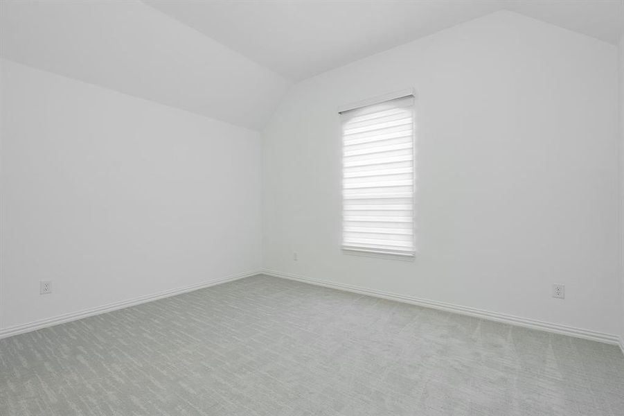 Empty room with lofted ceiling and carpet flooring
