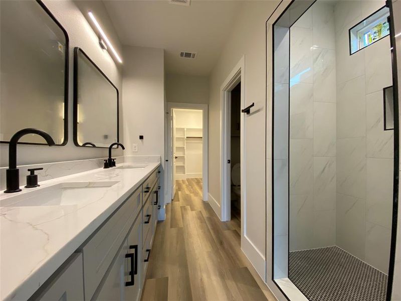 Bathroom with vanity, a tile shower, wood-type flooring, and toilet