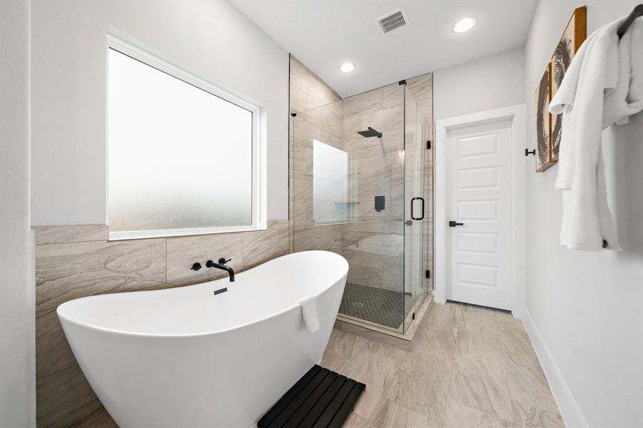 Master bathroom exudes opulence with dual vanities, a freestanding soaking tub, and a spacious shower, combining luxury with function.