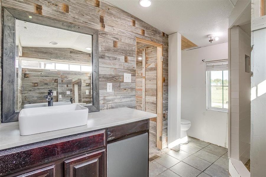 Bathroom featuring a textured ceiling, vanity, tile patterned flooring, toilet, and lofted ceiling