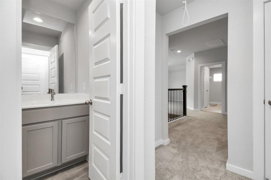 The secondary bath includes modern tile flooring, a combined bath and shower with a tile surround, light wood cabinetry, and a beautiful light-colored countertop. Sample photo of completed home with similar floor plan. Actual colors and selections may vary.