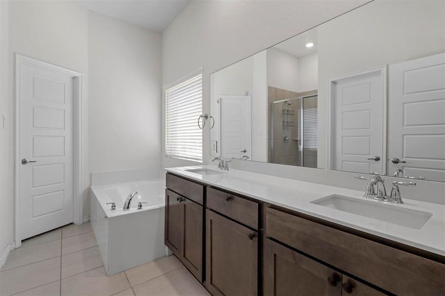 Bathroom with dual bowl vanity, tile flooring, and separate shower and tub