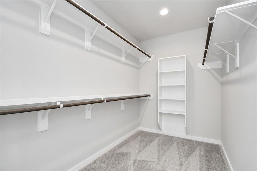 This generously sized walk in closet features built-in shelving, offering abundant room for impeccable organization. Sample photo of completed home. Actual color and selections may vary.