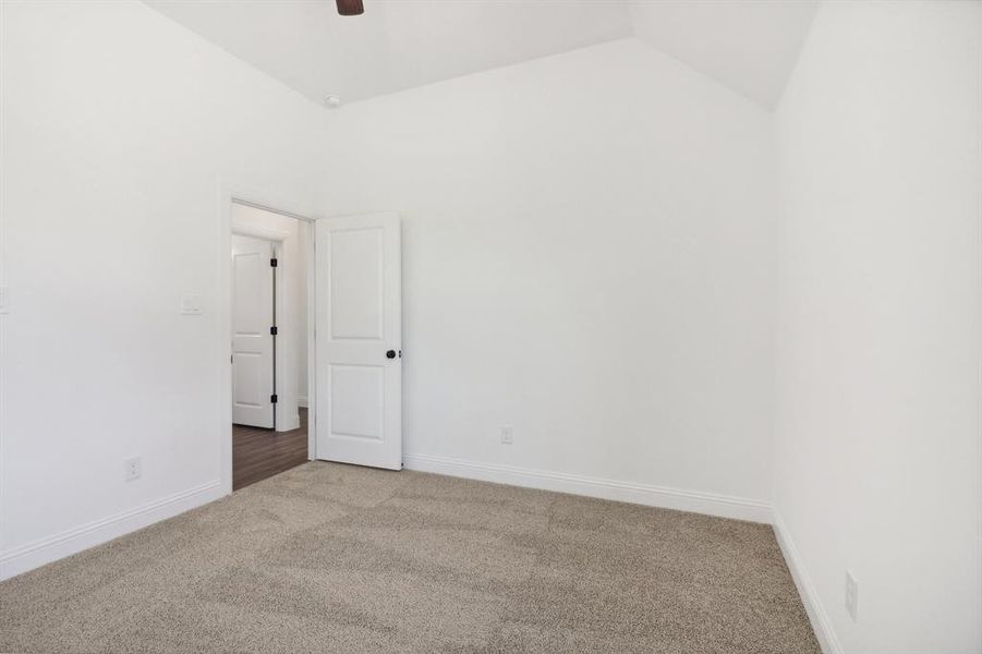 Carpeted spare room featuring ceiling fan and lofted ceiling