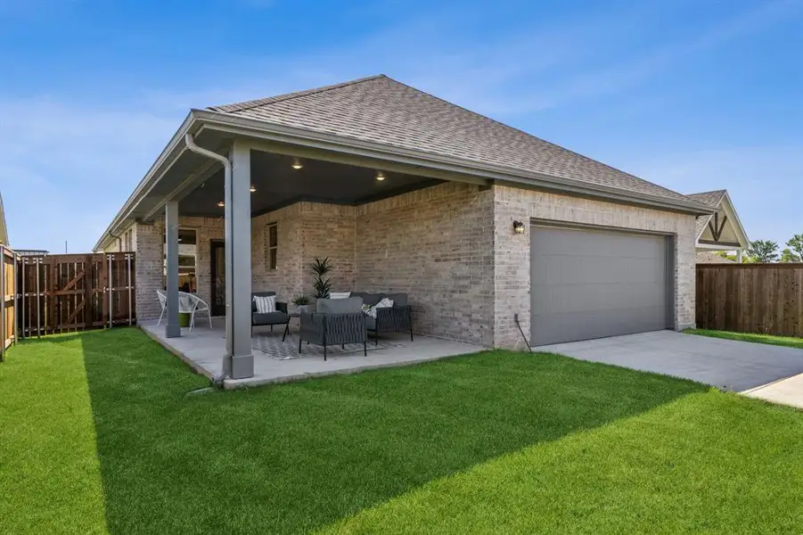 Rear view of property with an outdoor living space, a patio area, a yard, and a garage