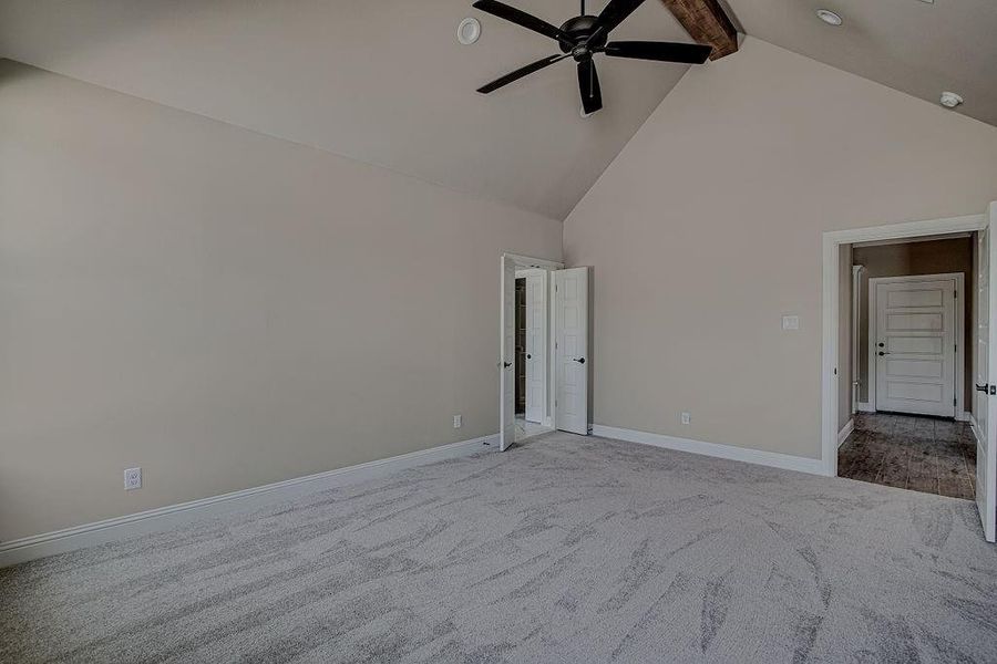 Unfurnished room featuring ceiling fan, beamed ceiling, light colored carpet, and high vaulted ceiling