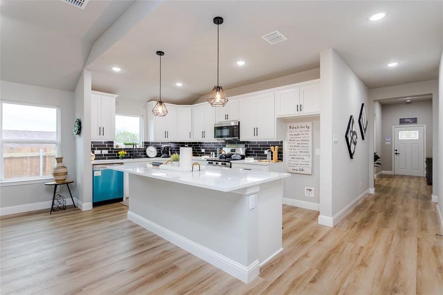 Kitchen featuring stainless steel appliances, light wood-type flooring, a kitchen island, and white cabinets