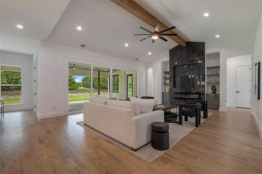 Living room featuring plenty of natural light, ceiling fan, beamed ceiling, and light hardwood / wood-style flooring