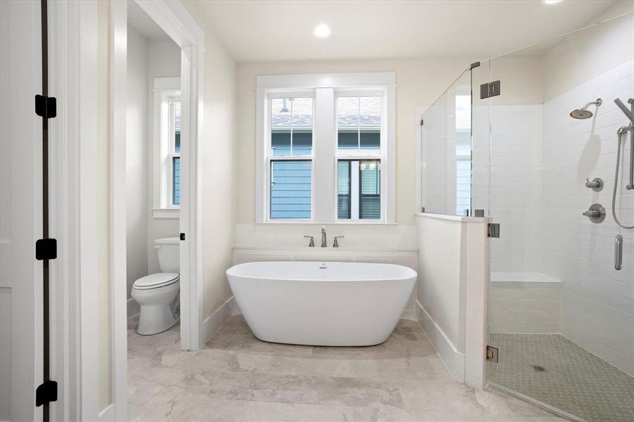 Bathroom featuring toilet and shower with separate bathtub