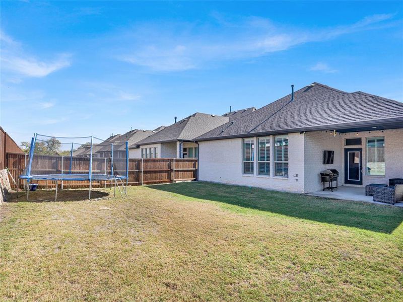 Rear view of house featuring a patio area and large grassy lawn.