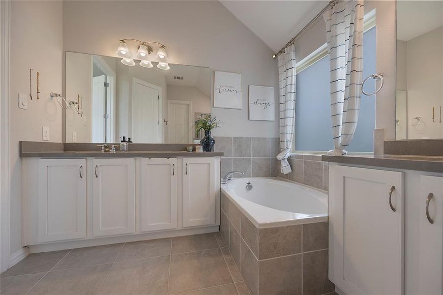 Bathroom with a wealth of natural light, vanity, lofted ceiling, and tile patterned floors