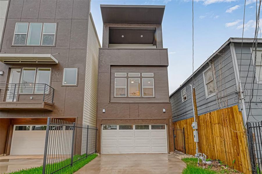 3 story modern townhome. Remote controlled garage with a driveway. The access gate on the right has number lock for safety. Can you see the third floor balcony?