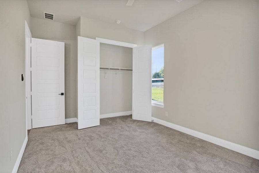 Unfurnished bedroom featuring ceiling fan, light colored carpet, and a closet