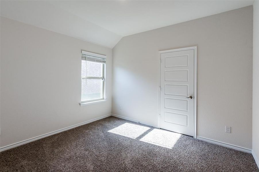 Carpeted spare room with vaulted ceiling