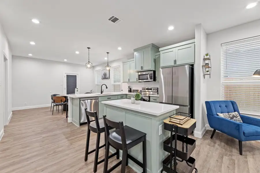 Kitchen with kitchen peninsula, sink, a kitchen bar, pendant lighting, and appliances with stainless steel finishes