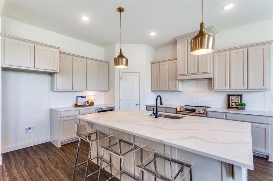 Kitchen with hanging light fixtures, sink, dark hardwood / wood-style floors, and a kitchen island with sink