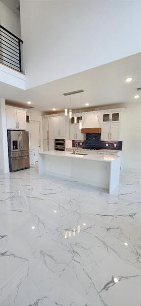 Kitchen featuring white cabinetry, a center island, pendant lighting, and stainless steel appliances