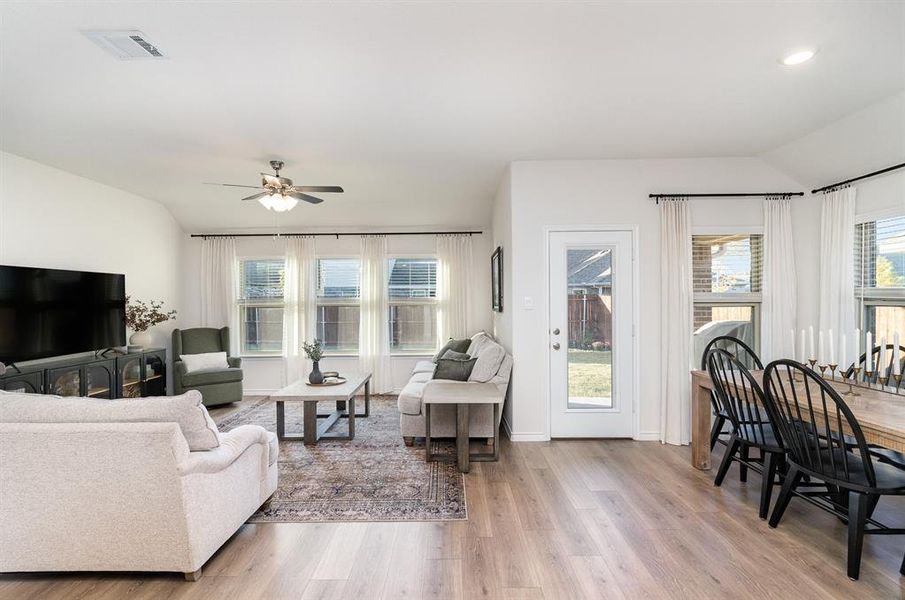 Living room with light hardwood / wood-style flooring, lofted ceiling, and ceiling fan