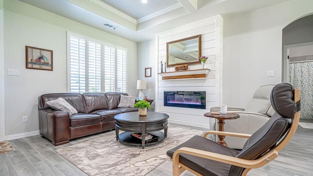 Living room with ornamental molding, a large fireplace, and light hardwood / wood-style floors