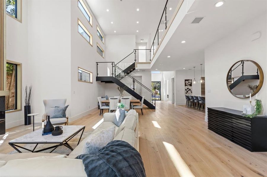 Living room with a towering ceiling and light hardwood / wood-style floors