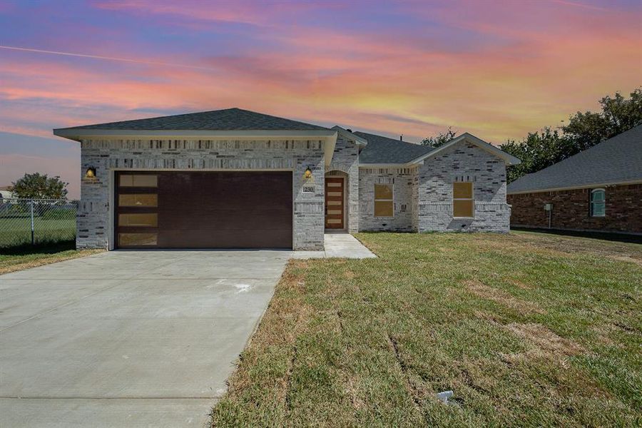 View of front of property featuring a lawn and a garage