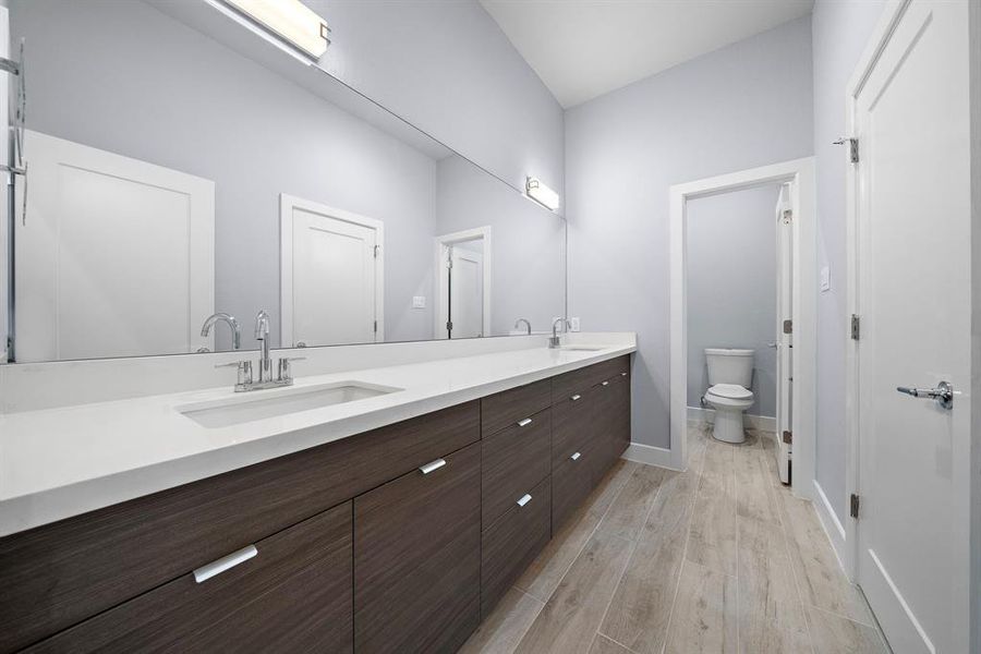 Well-appointed secondary bathroom with dual sinks and tons of storage.
