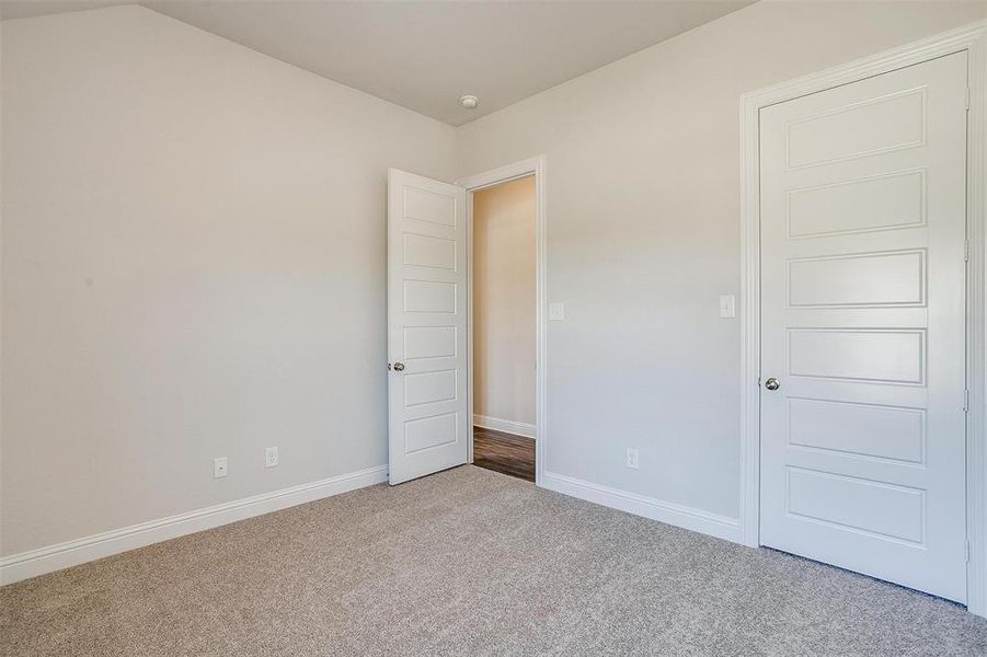 Unfurnished bedroom featuring light carpet and vaulted ceiling