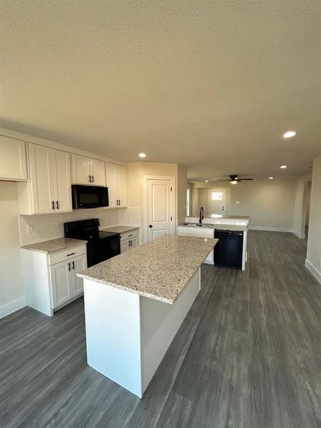 Kitchen featuring dishwasher, disposal, range, microwave, wood-style flooring, plenty of cabinets, and a center island