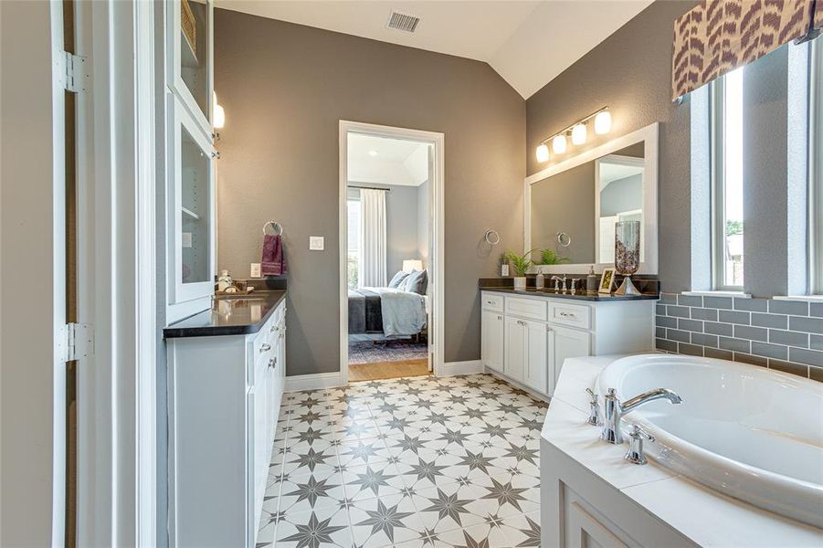 Bathroom with a healthy amount of sunlight, vanity, tile patterned floors, and a bath