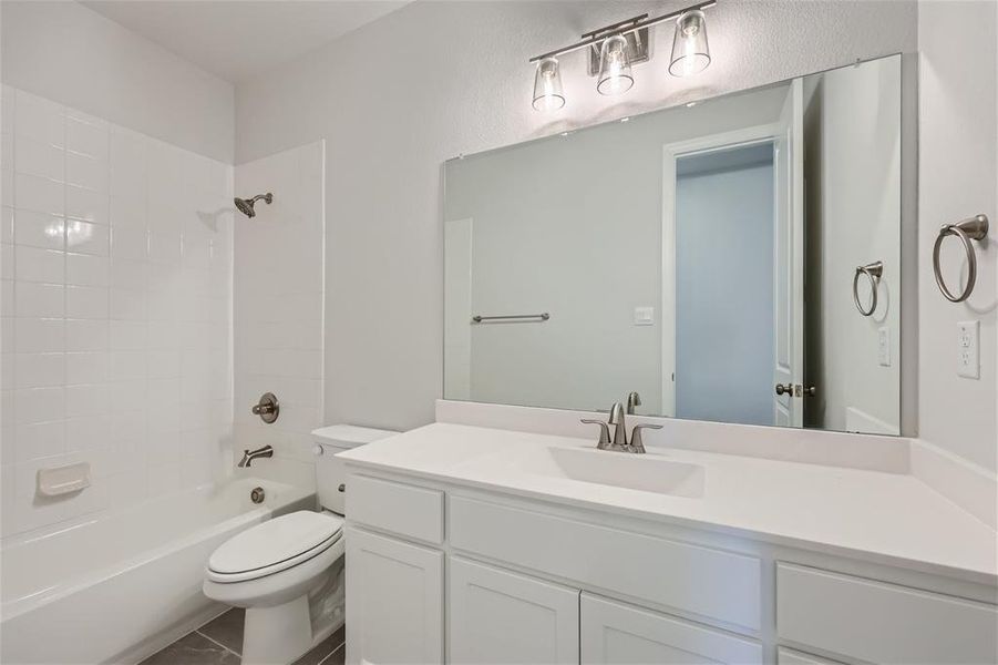 Full bathroom featuring tile flooring, oversized vanity, toilet, and tiled shower / bath combo