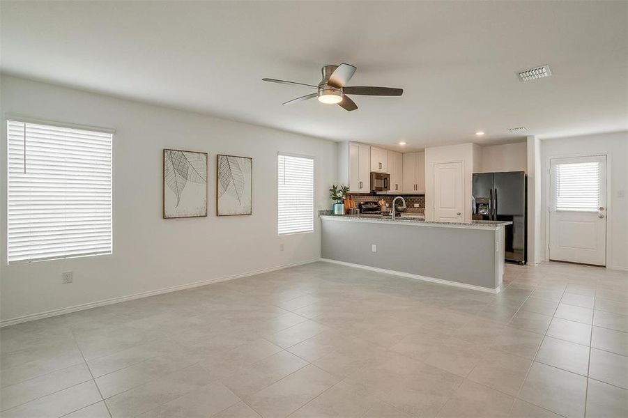 Kitchen featuring stainless steel fridge with ice dispenser, white cabinets, tasteful backsplash, light tile flooring, and ceiling fan