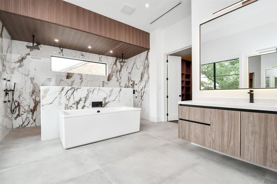 Experience luxury from every angle in this alternate view of the primary bath and vanity area. Modern finishes accentuate the sleek design, while massive mirrors, equipped with LEDs, amplify the sense of space and sophistication.