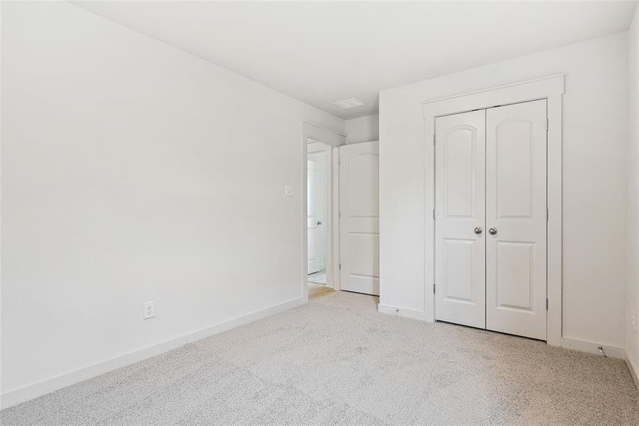 Unfurnished bedroom with light colored carpet and a closet