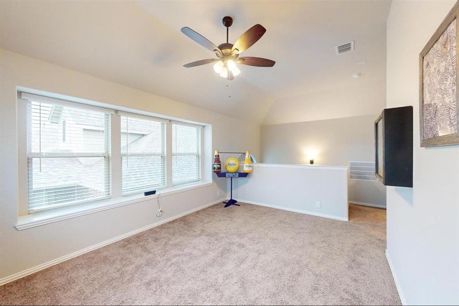 Spare room with plenty of natural light, ceiling fan, light colored carpet, and vaulted ceiling