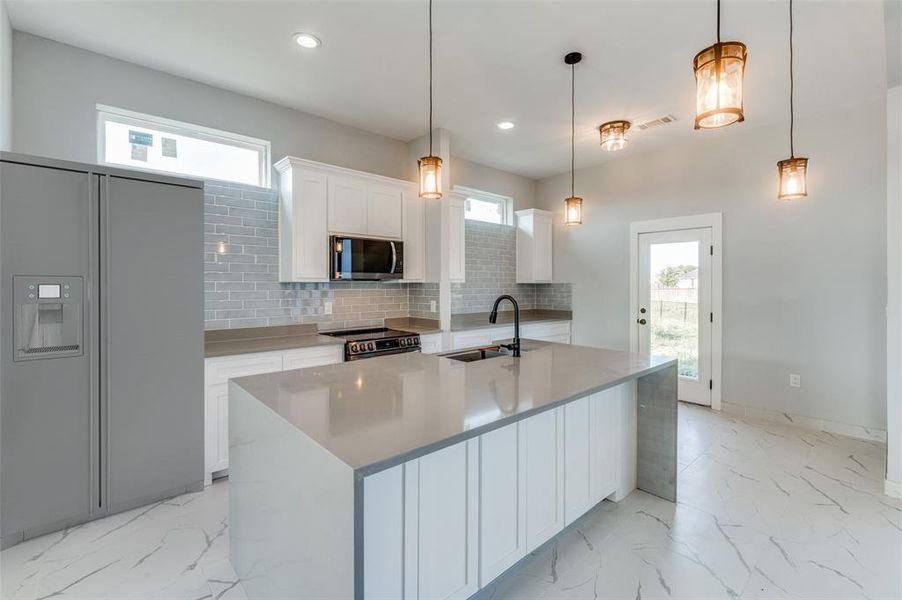 Kitchen with a healthy amount of sunlight, pendant lighting, sink, and appliances with stainless steel finishes