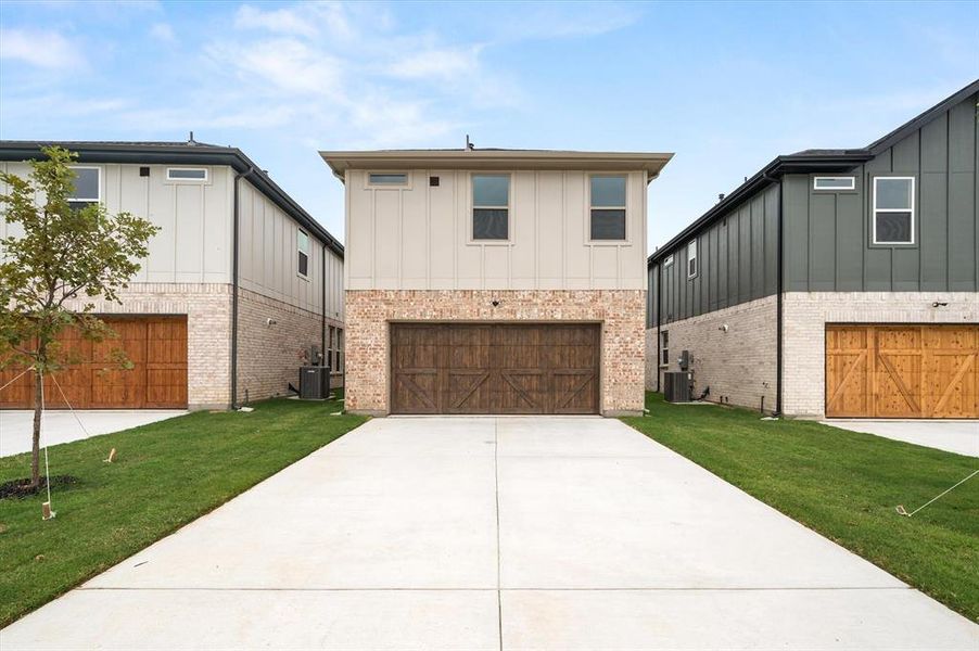 View of front of property with a garage, central AC unit, and a front yard