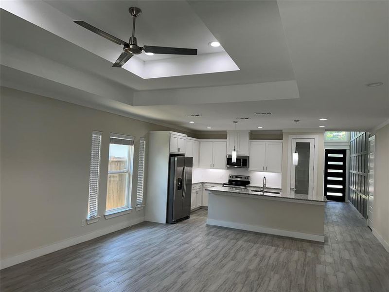 Kitchen featuring light wood-type tile flooring, appliances with stainless steel finishes, a tray ceiling, white real wood cabinets, and ultra contemporary ceiling fan.