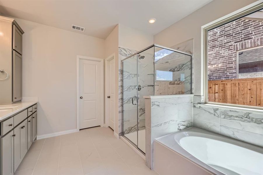 Primary bathroom with vanity, shower with separate bathtub, and tile patterned flooring