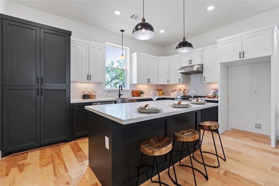 CMC Homes upgraded Plan A model now comes with a stainless steel vent hood, timeless herringbone ceramic tile backsplash, new island pendants with a new color combination creating a classic yet bold feel to a true quality build with custom wood cabinets built on-site.
