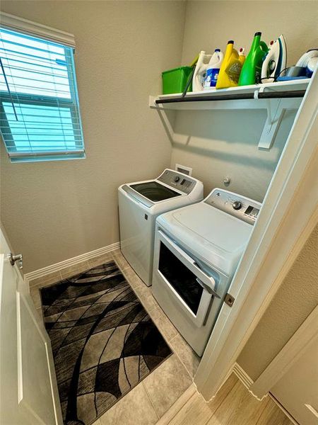 Washroom with light tile patterned floors and washing machine and clothes dryer