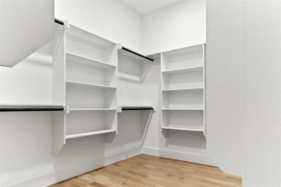 Walk in closet with light hardwood / wood-style flooring