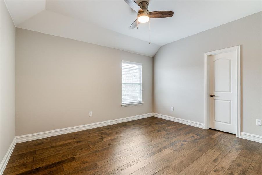 Empty room with lofted ceiling, ceiling fan, and dark hardwood / wood-style flooring