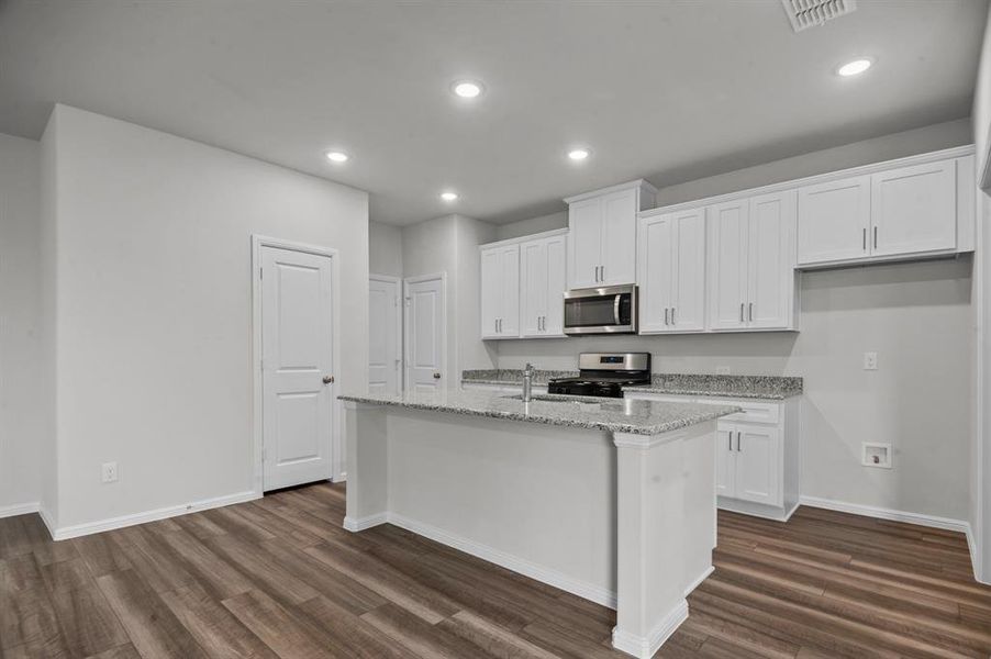 Kitchen featuring white cabinets, stainless steel appliances, a kitchen island with sink, and dark hardwood / wood-style floors