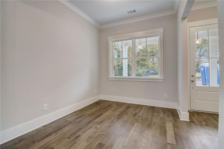 Empty room with a healthy amount of sunlight, ornamental molding, and dark hardwood / wood-style flooring