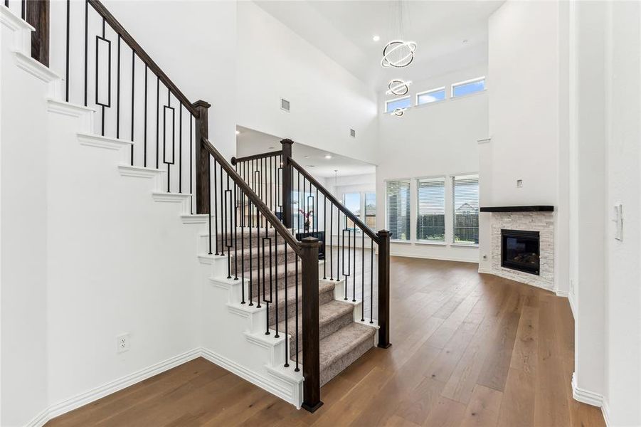 Stairway featuring a towering ceiling, hardwood / wood-style flooring, and a stone fireplace